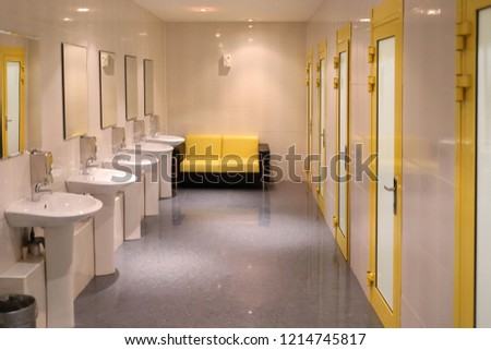 Empty clean public toilet with sinks, mirrors and cabins, sofa