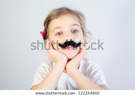 Little melancholy girl in white with glued fake black mustache.
