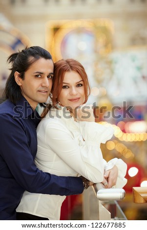 Dark-haired man embrace red-haired woman from behind