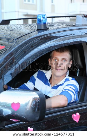 Young man at wheel of black wet  offroader with stickers hearts and blue flasher. Pink wedding.