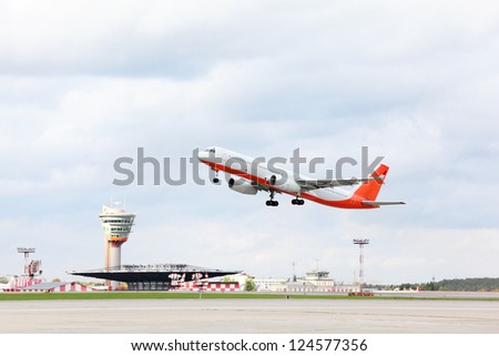 Large red and white passenger airplane takes off at airport.