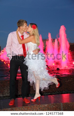 Young bride and groom kiss near pink fountains. Pink wedding.