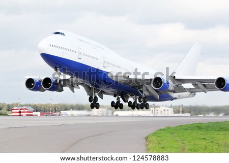 Large blue and white passenger airplane takes off at airport.