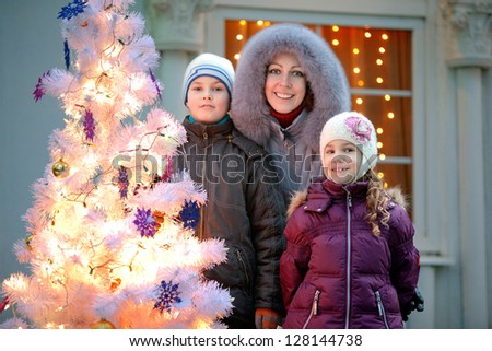 mother and two children near a New Year tree against ancient house