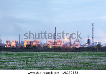 Industrial zone with factories and pipes with smoke and illumination at evening.