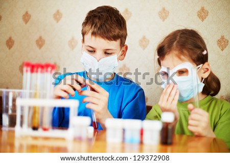 Boy fills chemical test tube with specimen and girl sits near to him, focus on boy face