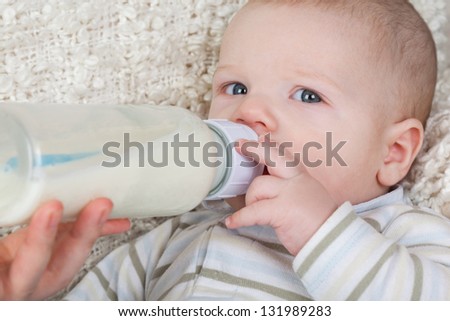 Portrait of a baby with a bottle in a striped blouse.