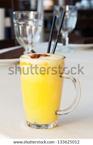 Tasty yellow cocktail with two sticks on the table.