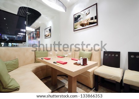 Wooden table, beige leather sofa and mirror in cozy Japanese restaurant.