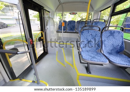 Seats in passenger compartment of empty city bus with big windows.