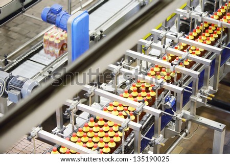 Top view of line with bottles of fresh light beer with red caps in modern beer factory.