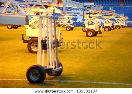Lighting system for growing grass at empty football stadium with blue seats.