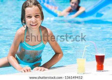 Girl with mother on the background out of the pool next to the glasses with drinks