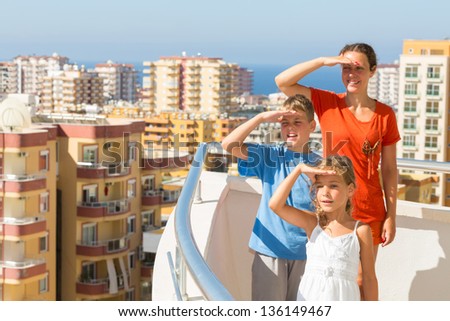 Family of three on the balcony of the room at the hotel looking into the distance on the top floor