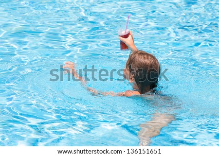 Girl swimming in the pool with a drink in hand