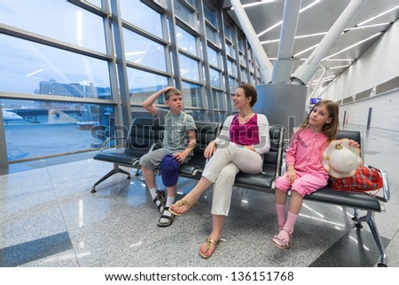A family of three sitting in a recreation area at the airport