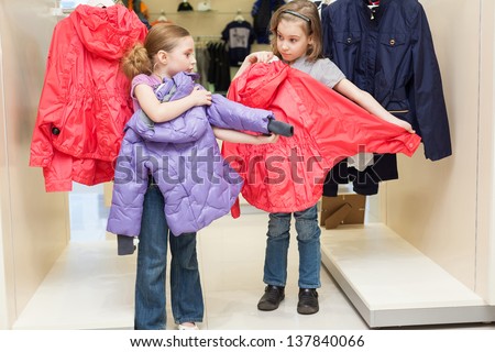 Two cute girls try on clothes in a modern store childrens clothes