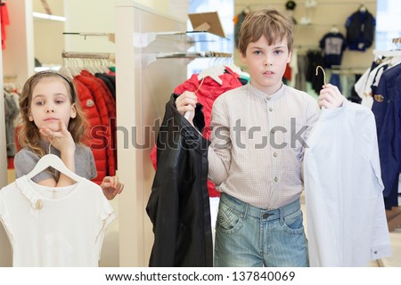 The boy with the girl trying on clothes in a store childrens clothes