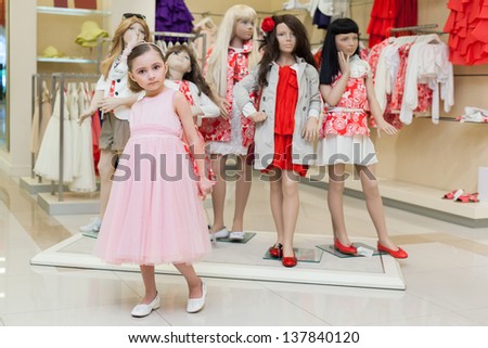 The girl in the store trying on a dress on a background of mannequins