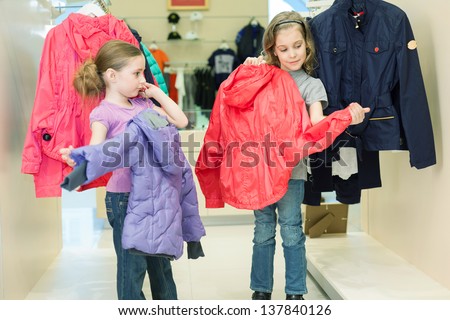 Two girls try on clothes in a store childrens clothes