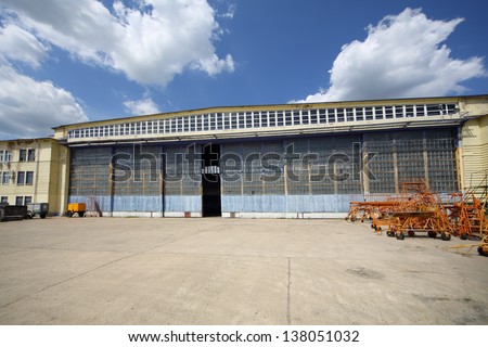 Big old battered aircraft hanger with big gate at sunny summer day.