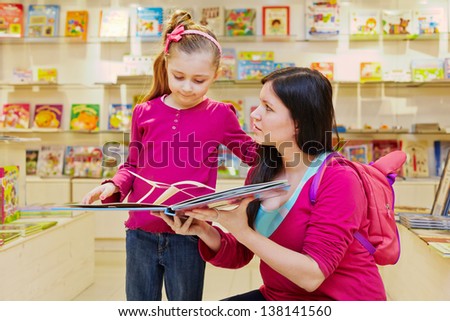 Mother shows to daughter big fold-out book in book department of store
