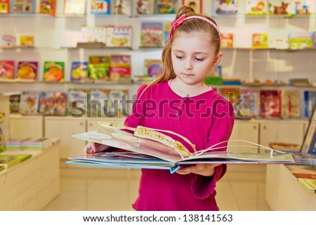 Little girl views fold-out book on anatomy in book department at store