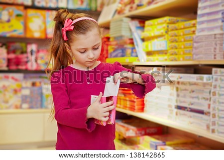 Little girl views box with envelopes in book department of store