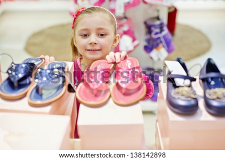Little girl looks up on toeless shoes that stands on top of shoe boxes