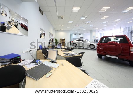 New beautiful cars stand in big office of shop selling cars.