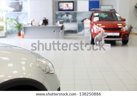 Headlight Of New White Car Standing In Office Of Shop Selling Cars.