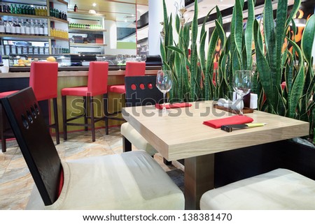 Square table with glasses and bar in hall of cozy Japanese restaurant.