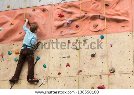 Young climber rises to the climbing wall.