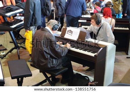MOSCOW - SEP 22: Young and old people playing the keyboards with headphones on XVIII International Exhibition of Music Moscow 2012 in Sokolniki on September 22, 2012 in Moscow, Russia.