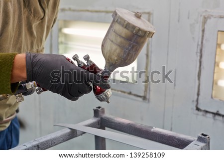 Male hand in glove with spray paint gun, painting car details