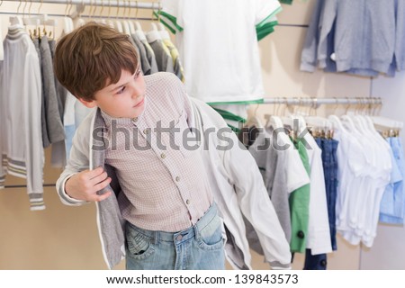 The boy tries on clothes in the childrens clothing store