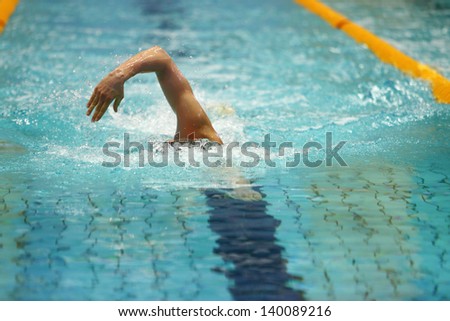 Front view of man swims  in a swimming pool, crawl