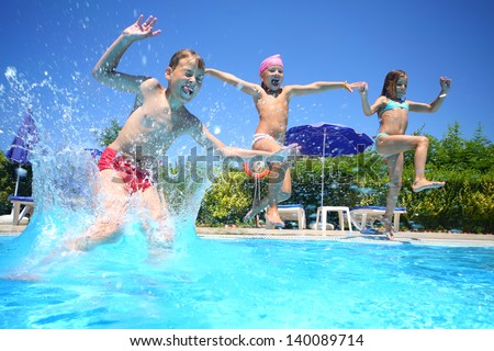 Two little girls and boy fun jumping into the swimming pool, shot through the underwater package.