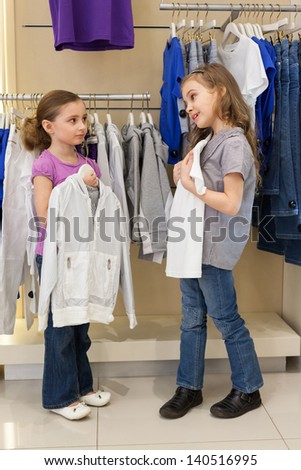 Two little girls try on clothes in a store children clothes