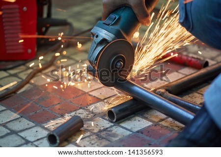 Male hand cuts off pieces of water pipe with angle grinder
