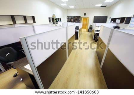 Corridor with wooden floor and empty working areas with desktops in office.