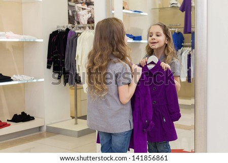 Cute little girl near a mirror try on clothes in a store childrens clothes