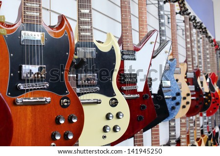 Many electric guitars hanging on wall in the shop