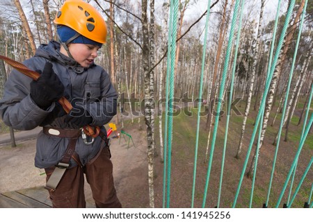 Boy climber preparing to the passage ropes course