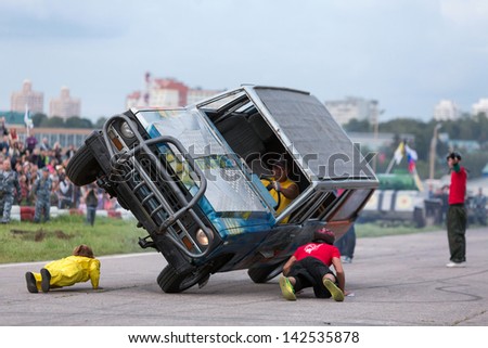 MOSCOW - AUG 25: Stuntman lie under to passing a car on two wheels on Festival of art and film stunt Prometheus in Tushino on August 25, 2012 in Moscow, Russia. The festival was organized in 1998.