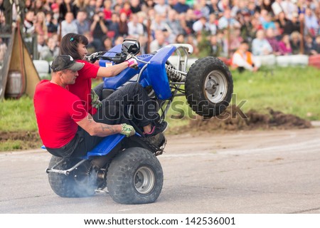MOSCOW - AUG 25: Man with girl rides on the rear wheels on a quad bike on Festival of art and film stunt Prometheus in Tushino on August 25, 2012 in Moscow, Russia. The festival was organized in 1998.