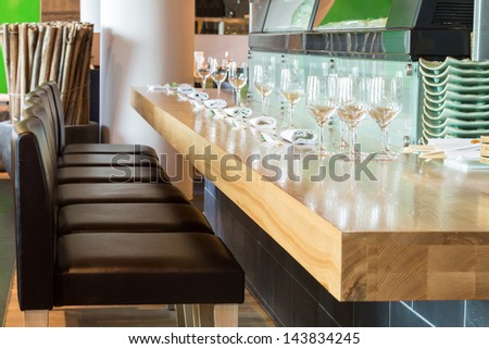 Long table with glasses in the cozy cafe with modern interior.
