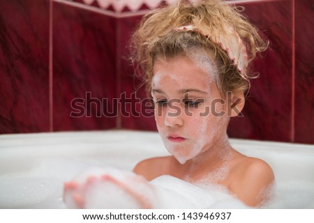 Little girl taking a bath with foam on his face