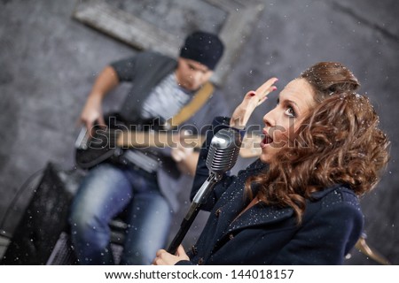Female lead vocalist and guitarist in studio during shooting videp clip, turned frame
