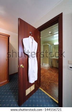 Entrance door to bathroom open. On door hangs white terry bathrobe.